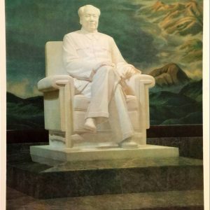 White marble statue of Mao Zedong seated in an armchair before a mountain landscape tapestry in his Beijing mausoleum.